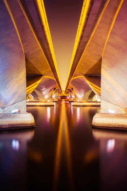 Two bridges at night spanning a body of water with symmetric architecture.