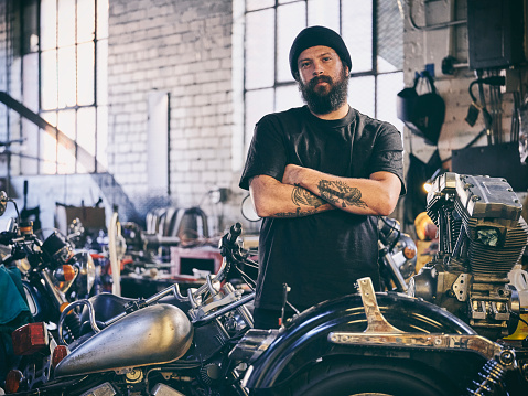 A motorcycle mechanic working in an old fashioned retro style cycle repair shop.