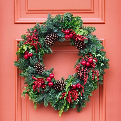 front door with Christmas wreath made of pine branches, pine cones, and red berries