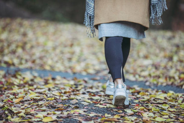 istock Women's foot walking on fallen leaves 1087032326
