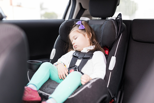 Adorable sweet girl sleeping peacefully on safety seat in car