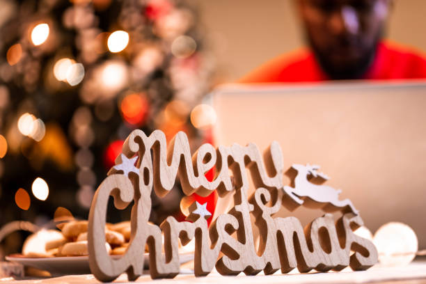 African-American man using a laptop and a mobile phone at home at Christmas.