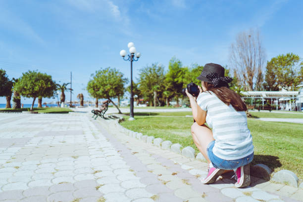 Young female photographer taking photos at the seaside promenade