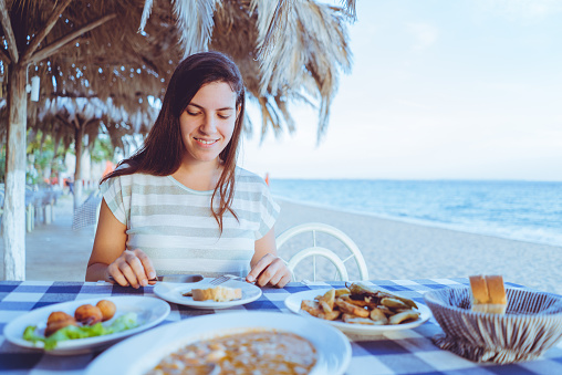 Woman eating in a seaside restaurant