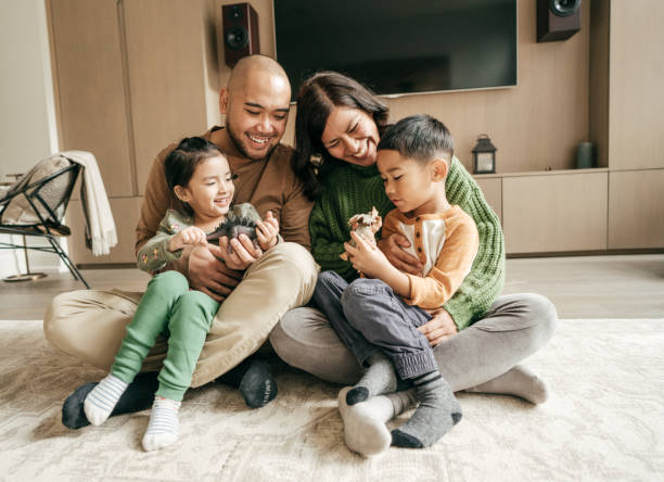 familie im wohnzimmer auf dem boden sitzend - ostasiatischer abstammung fotos stock-fotos und bilder