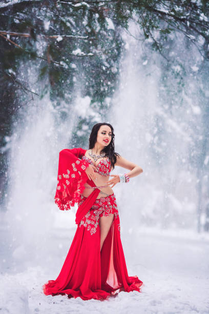 schöne junge mädchen tanzen bauchtanz im roten kleid im winter in einem park auf dem schnee. - arabia belly dancing dancing women stock-fotos und bilder