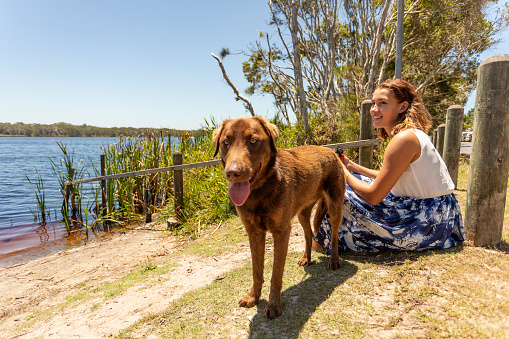 Young woman sitting with her dog looking at a lake