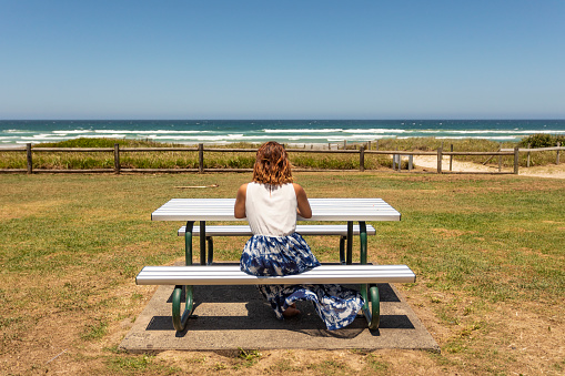 Young Woman Sitting Thinking at a Picnic Seat by the Beach