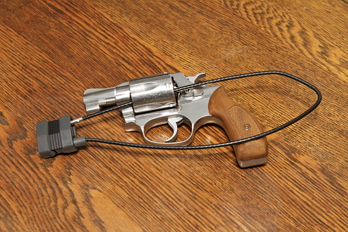 Revolver on table with cable padlock securing open bullet cylinder.