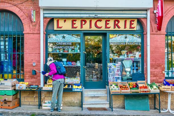 un cliente femenino de las compras de productos frescos fuera de una tienda tradicional pequeño supermercado francés de provenza. - newspaper france photography horizontal fotografías e imágenes de stock