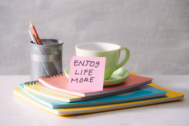 istock Green cup, notebooks and sticker with text - enjoy life more on light background. Toned business concept with copy space 1087089520