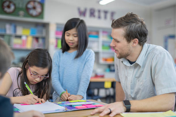 istock A male teacher helps two 4th grade students 1087099086