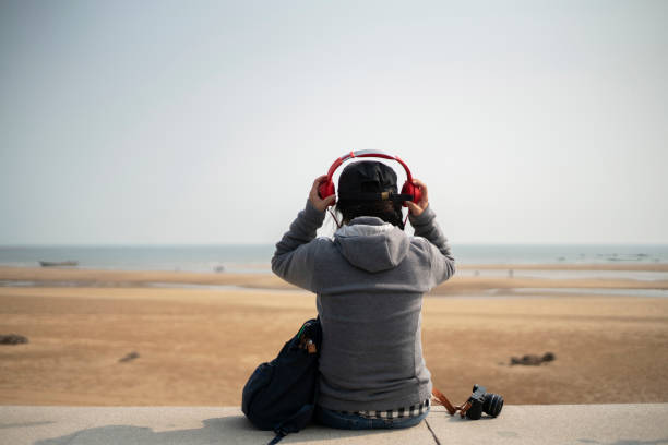 istock young female wearing headphone resting on beach 1087104448