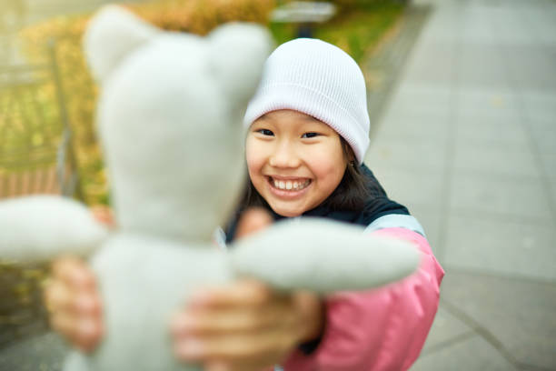 Toddler girl holding her favorite toy on a sunny day in a park