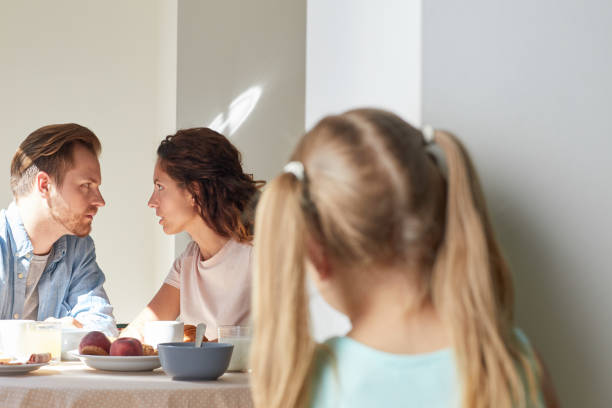 Talk of parents Young man and woman having intimate talk by breakfast while their daughter eavesdropping by kitchen door eavesdropping stock pictures, royalty-free photos & images