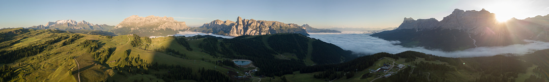 Dolomites, Italy. Amazing drone aerial landscape at Sella, Gardenaccia Fanes and Marmolada massifs. Fog at the bottom of the valley during summer time