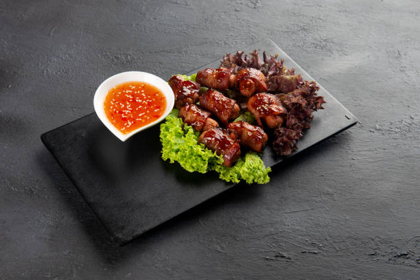 istock Pigs in blankets. Mini sausages wrapped in smoked bacon in baking dish 1087117886