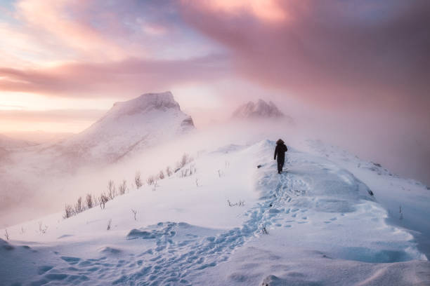 mann bergsteiger zu fuß mit schnee fußabdruck auf gipfel schneegrat blizzard - winter sunrise mountain snow stock-fotos und bilder