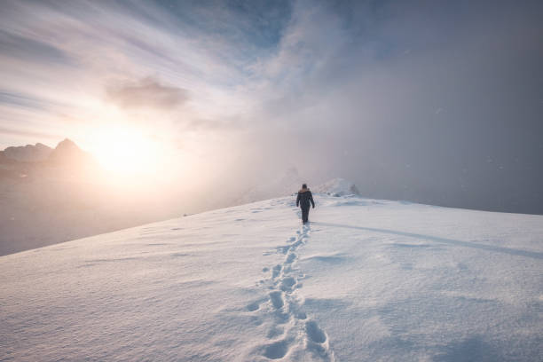 istock Man mountaineer walking with snow footprint on peak ridge 1087125330