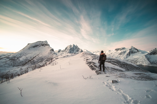 Mountaineer standing on top of snowy mountain at sunlight morning