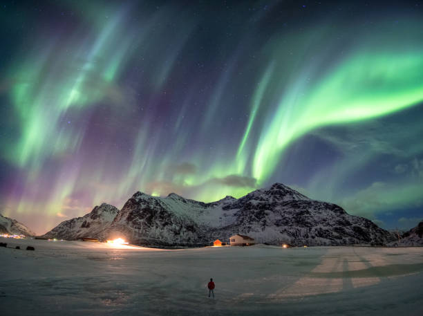 istock Fantastic Aurora borealis over snowy mountain with man standing 1087125354