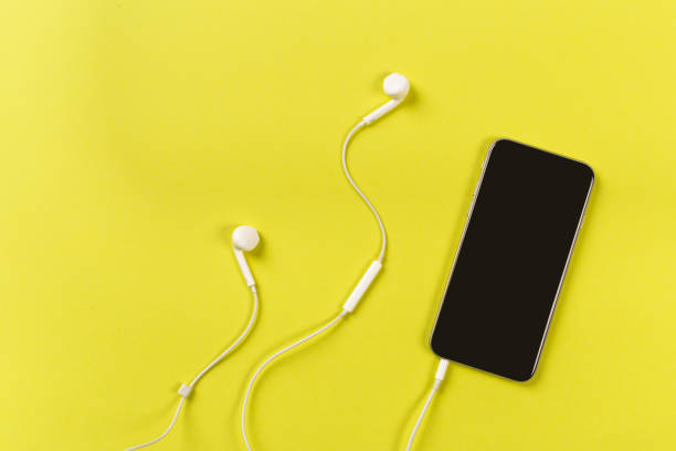 istock Mobile phone with white earphones on colour backgroung, top view 1087129052