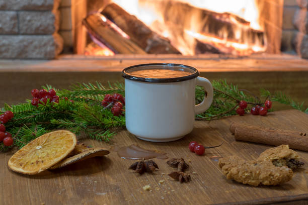 istock Cozy scene before fireplace with enameled white mug of hot chocolate, mulled fruit. 1087140128
