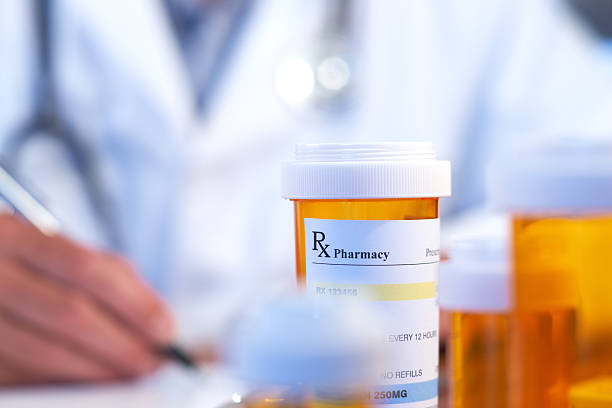 Blurred doctor behind orange prescription bottle stock photo