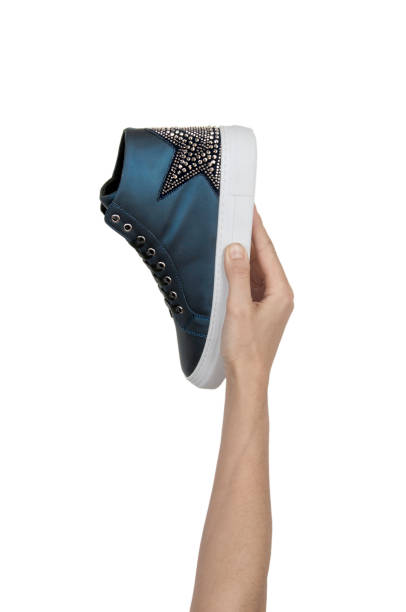 istock Female hand holding navy blue shoe 1087146494