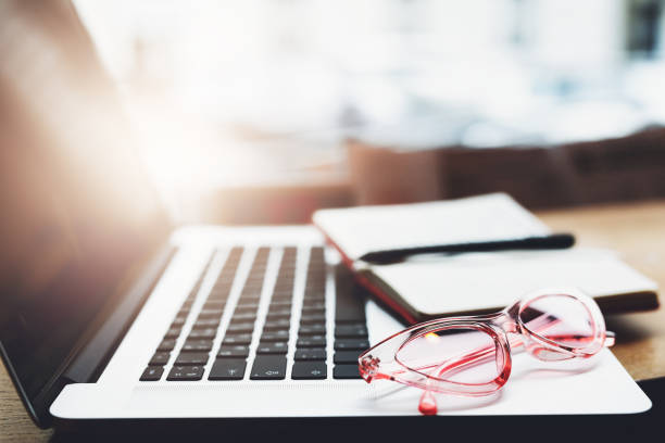 istock Laptop, glasses and note papers on table with blur background. Copy space. - Image 1087149578