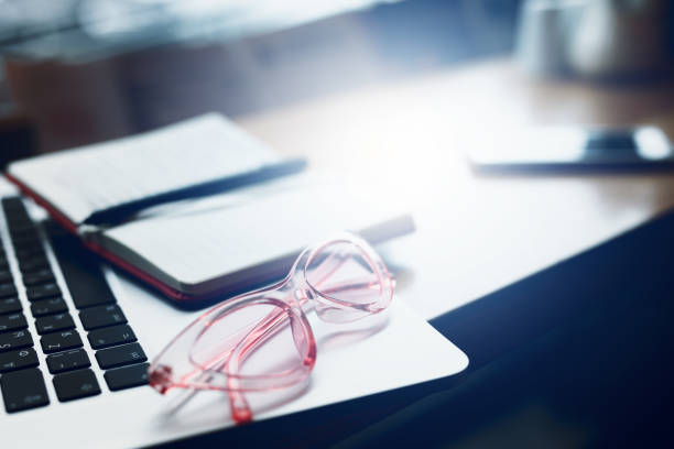 istock Laptop, glasses and note papers on table with blur background. Copy space. - Image 1087149584