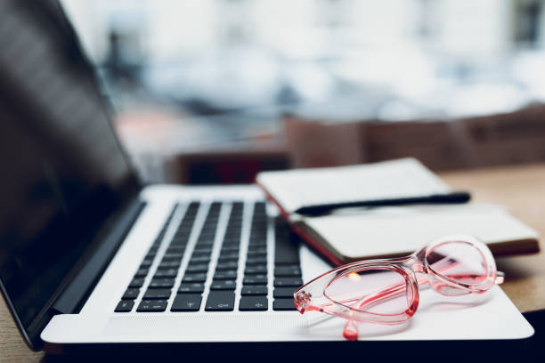 istock Laptop, glasses and note papers on table with blur background. Copy space. - Image 1087149586