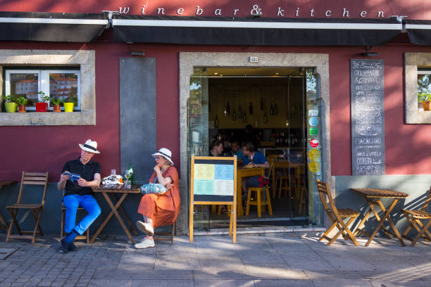 A couple of tourists have a drink on the terrace of a bar while consulting a city guide in Porto.