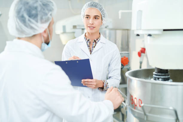 istock Confectionery factory worker taking notes talking to colleague 1087171462