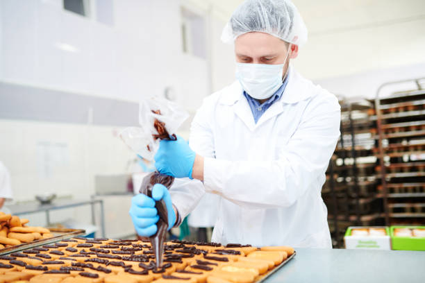 istock Confectionery factory worker decorating pastry using icing bag 1087171546