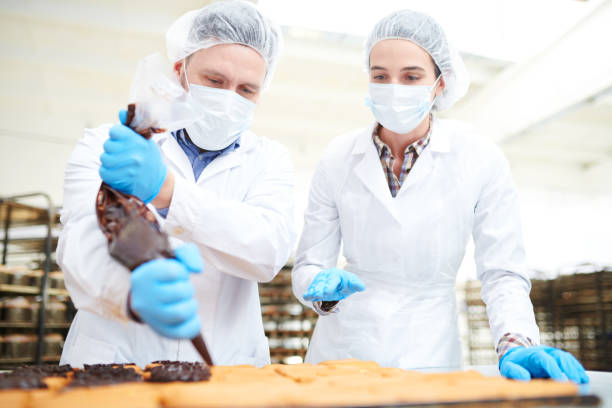 Confectioners pouring chocolate cream from pastry bag