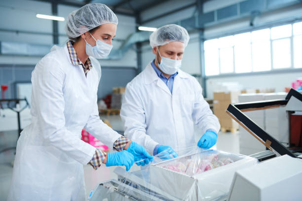 istock Confectionery factory workers wrapping box into packaging film 1087171604