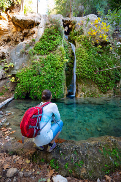 viaggiatore, donna ammira cascata che scorre lungo la scogliera - waterfall zen like women meditating foto e immagini stock