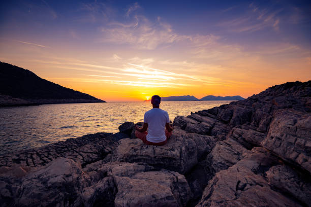 istock Traveler sits on the rock seashore and practicing yoga 1087181806