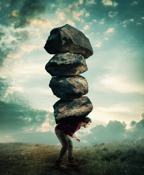 Man carries a stack of heavy rocks. stock photo