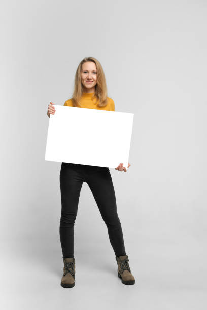 giovane donna sorridente con poster - holding a sign foto e immagini stock