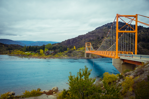 Puente de suspensión rojo sobre el escurrimiento del agua del lago General Carrera, lago Bertrand, Puerto Tranquilo, Chile Chico, Aysen, Chile photo