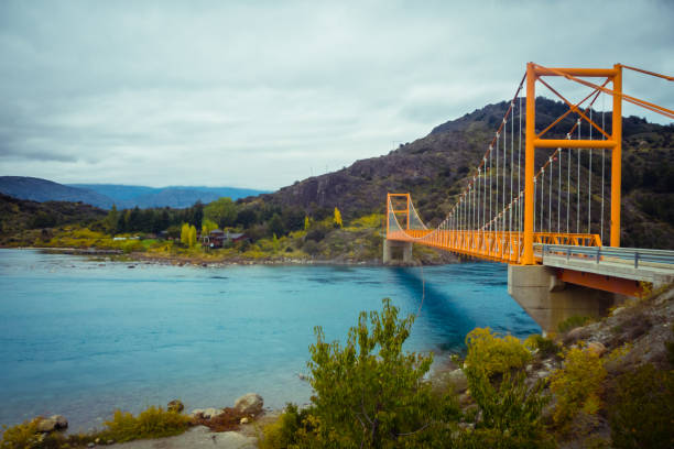 Red suspension bridge over the water runoff of General Carrera Lake, near Lake Bertrand, Puerto Tranquilo, Chile Chico, Aysen, Chile stock photo