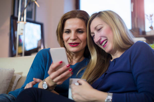 istock Two Cheerful Women Using Smart Phone At Home 1087189080