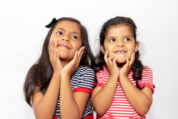 istock Cute sisters with striped dresses laughing 1087191608