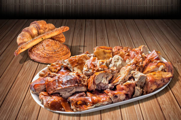 плита свежей косы жареного свинины мясо ломтики и пучок кунжута круассан слоеное тесто предлагается на rustic slatted бамбуковый стол - spit roasted pig roasted food стоковые фото и изображения