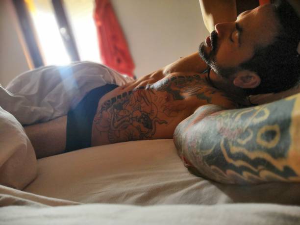 istock Shirtless man with tattoos sleeping in bed 1087197674