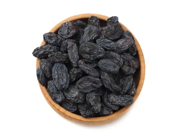 Photo of black raisins in wooden bowl isolated on white background. top view