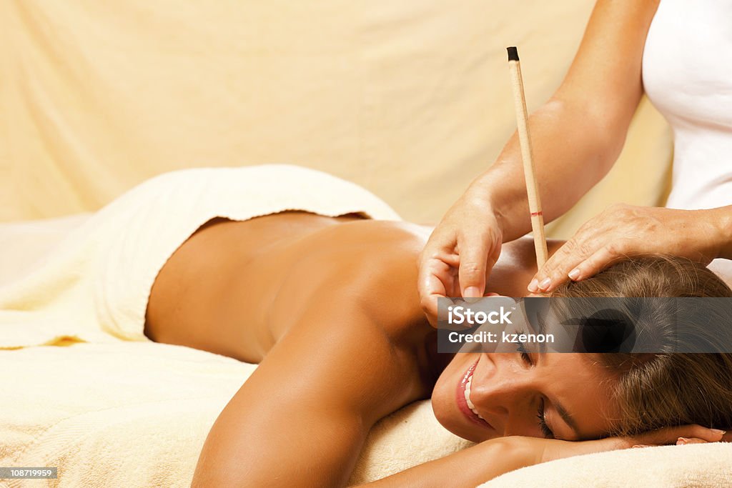 Woman with ear candles and gem massage Woman in wellness and spa setting having with ear candles and gem massage Ear Candling Stock Photo