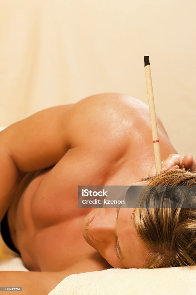 Man in therapy with ear candles Man in wellness and spa setting with ear candles having an alternative therapy session Ear Candling Stock Photo